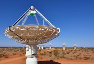 Large telescope in the foreground with more stretching into the distance at the Murchison Radioastronomy Observatory.