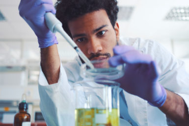 Scientist working with a pipette and laboratory equipment.