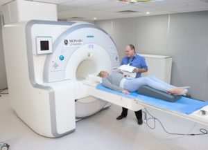A person lying on the MRI-PET scanner platform being prepared for a scan by a health professional.